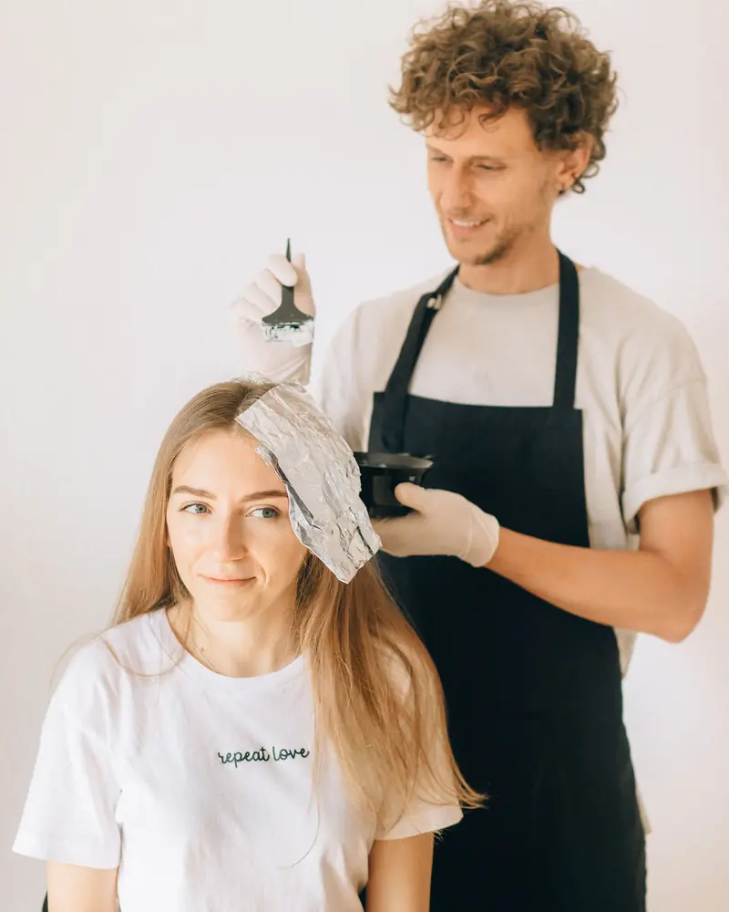 Stylist applying colour foils to a client with long blonde hair