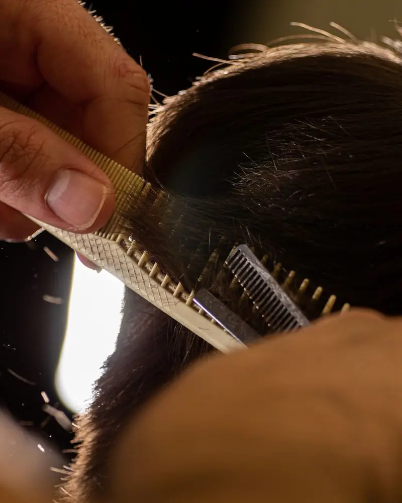 Close-up of a stylist cutting hair with a comb