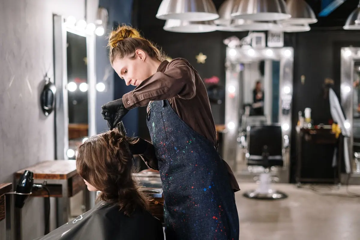 Stylist applying colour to a client's hair at the basin station